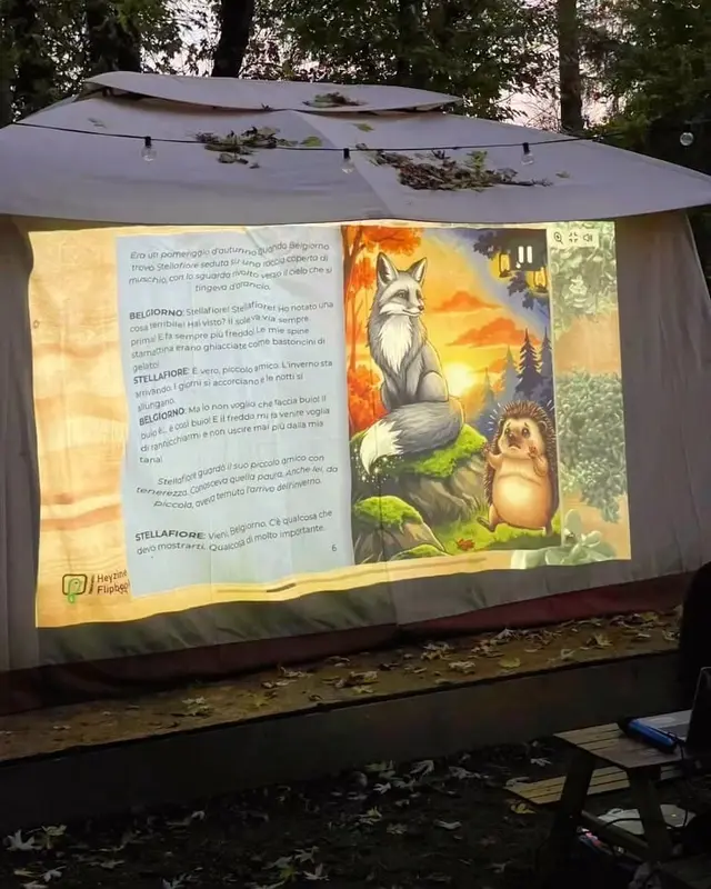 La lettura animata dello scorso anno: una pagina del libro, con la volpe e il riccio, proiettata sul telo del palco all'imbrunire